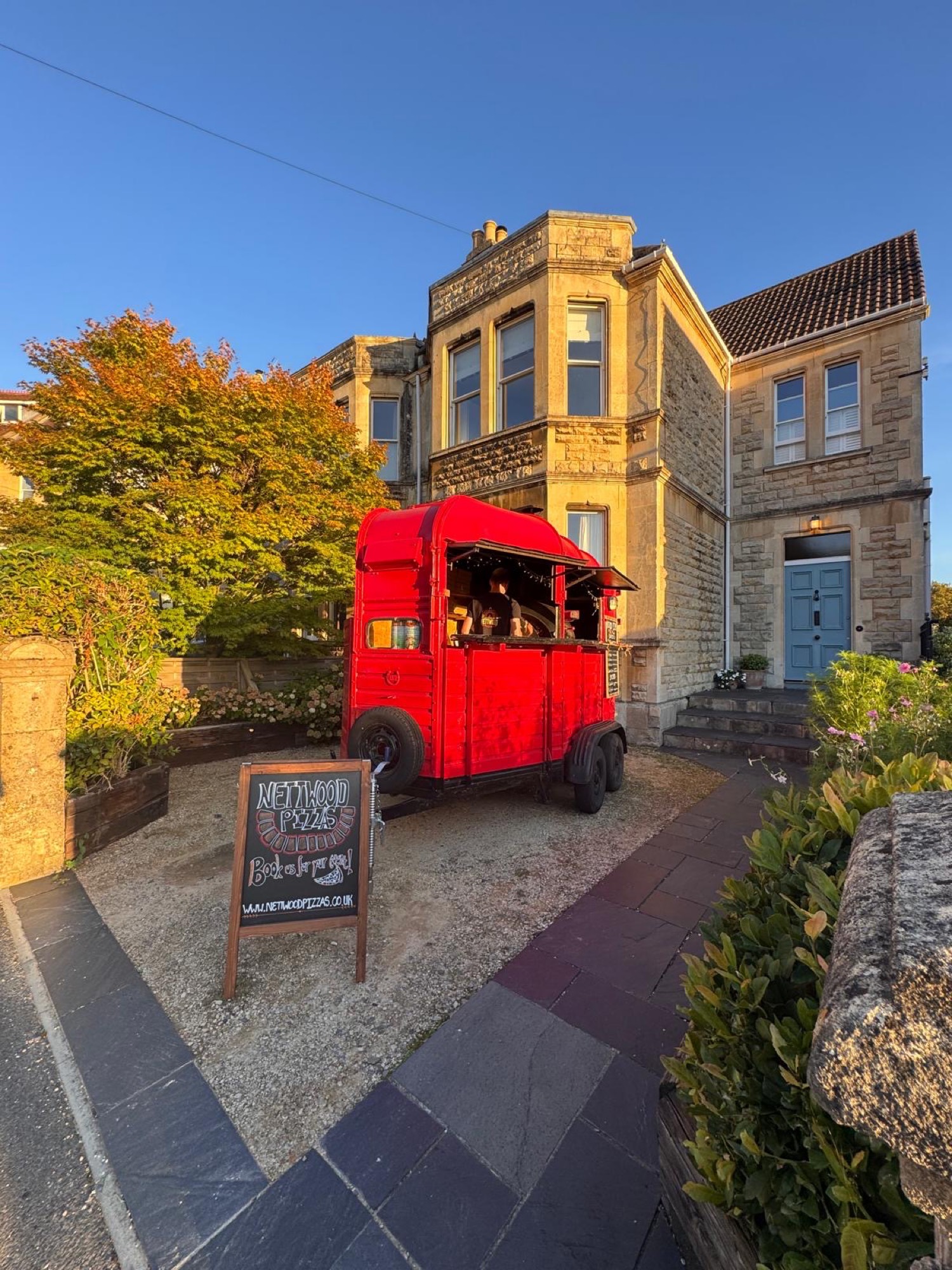 The horsebox on a gravel drive in front of a honey-coloured stone house